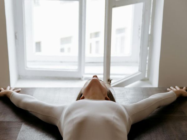 Person stretching gracefully in front of a window at sunrise.