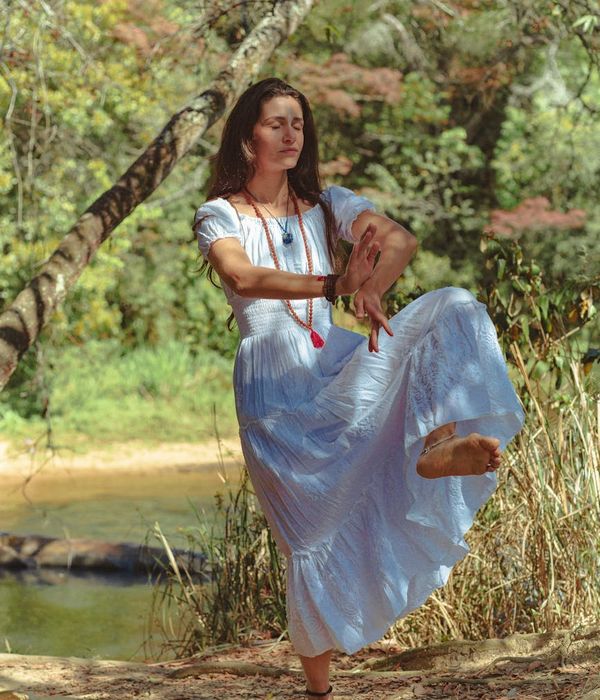 Woman in a calm meditation pose surrounded by nature.