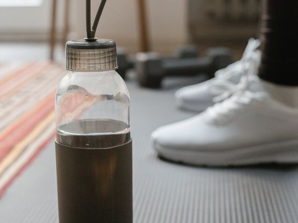 Yoga mat rolled up next to a water bottle and a small towel.